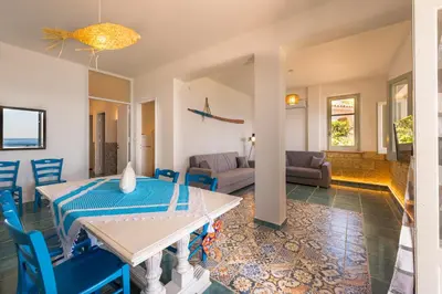a living room with a table and blue chairs at Dimore di mare - Beachfront Apartments in Santa Flavia