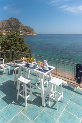 a white table and chairs on a balcony with the ocean at Dimore di mare - Beachfront Apartments in Santa Flavia