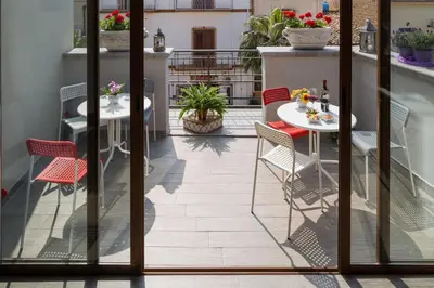 a patio with tables and chairs on a balcony at Arricàmpati Airport Rooms & Bringo Car Rental in Carini