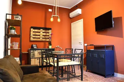a living room with an orange wall with a table and chairs at Piazza Marina in Palermo