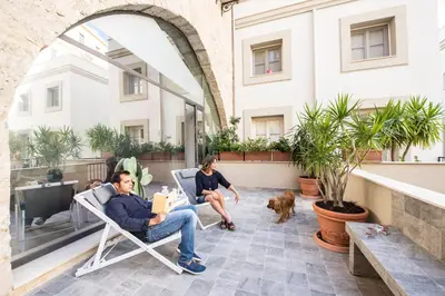 two people sitting in chairs on a patio with a dog at Gattopardo Apartments - LAGO Design by Wonderful Italy in Palermo