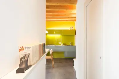 a kitchen with yellow cabinets and a table with a book at Gattopardo Apartments - LAGO Design by Wonderful Italy in Palermo