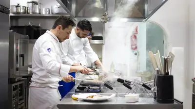 two chefs standing in a kitchen preparing food at Hotel Castello di Giuliano in Montelepre
