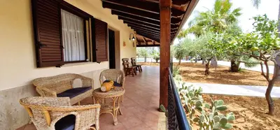 a porch with wicker chairs and a table with a teddy bear on top at Villa Paradiso in Alcamo Marina