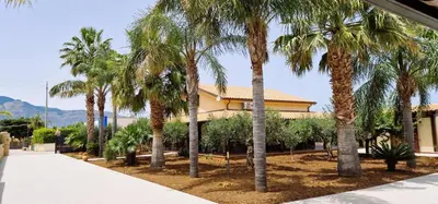 a group of palm trees in front of a building at Villa Paradiso in Alcamo Marina