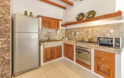 a kitchen with a stainless steel refrigerator and wooden cabinets at Villa Belvedere in Sambuca di Sicilia