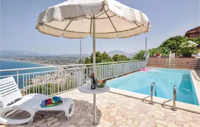 an umbrella and a chair next to a swimming pool at Villa Belvedere in Castellammare del Golfo