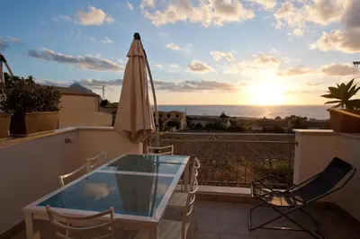 a patio with a glass table and a umbrella at Casa Azzurra by Un mare di Blu in Macari
