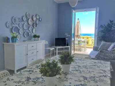 a living room with a table and a view of the ocean at Casa Azzurra by Un mare di Blu in Macari
