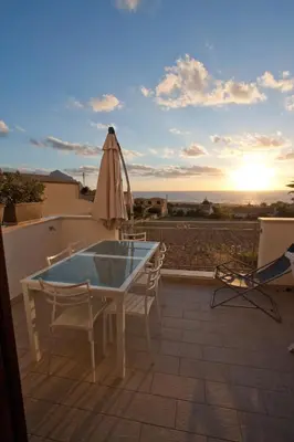 a patio with a table and chairs and an umbrella at Casa Azzurra by Un mare di Blu in Macari