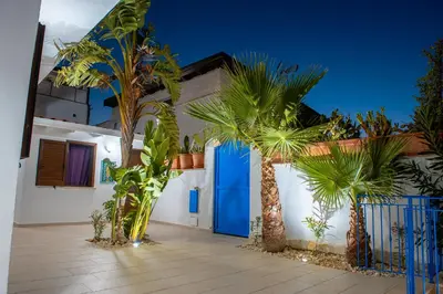 a house with palm trees in front of a blue door at Villa Oleandro in Alcamo Marina