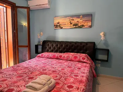 a bedroom with a bed with a red comforter at Belmonte Blu Suite in Palermo