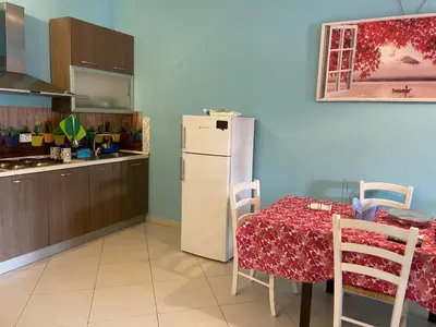 a kitchen with a table and a white refrigerator at Belmonte Blu Suite in Palermo