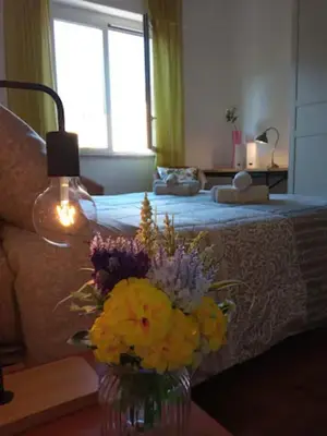 a vase of flowers on a table next to a bed at Casa del Cioccolato in Palermo