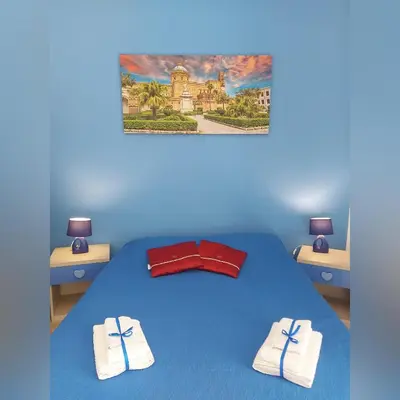 a blue bedroom with a bed with towels on it at B&B D'Amico87 in Bagheria