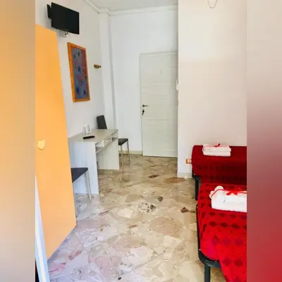 a room with two beds and a desk and a table at B&B D'Amico87 in Bagheria