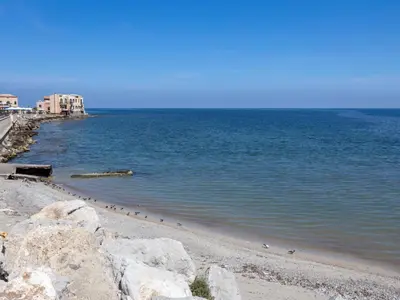 a beach with some rocks and water and buildings at Apartment Cicladi Milos by Interhome in Santa Flavia