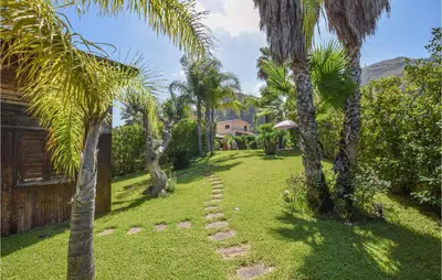 a garden with palm trees and a path at Villa Tourig Beach in Mandra Capreria