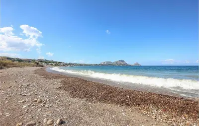 a beach with rocks and the ocean on a sunny day at Villa Tourig Beach in Mandra Capreria