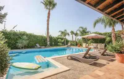 a swimming pool with chairs and an umbrella and palm trees at Villa Tourig Beach in Mandra Capreria