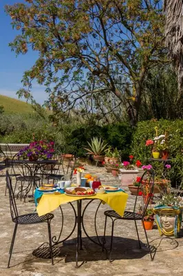 a table with a yellow table cloth on it with chairs at Agriturismo Tarantola in Alcamo