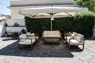 a group of chairs and an umbrella on a patio at Ciuri Ciuri Mondello in Mondello