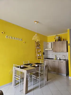 a kitchen with yellow walls and a table and chairs at Appartamento Girasole in San Vito lo Capo