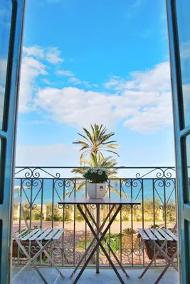 a table and chairs on a balcony with a palm tree at Le Luminarie - Creative Residence in Balestrate