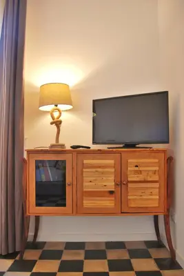 a television on top of a wooden cabinet with a lamp at Le Luminarie - Creative Residence in Balestrate