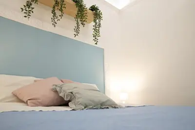a bedroom with a bed with a plant on the headboard at Voilà Rooms Guest House in Terrasini