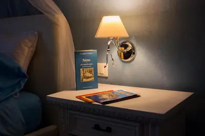 a table with a lamp and a book on it next to a bed at A Casa Di Lilly in Palermo