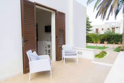 a patio with two chairs and a sliding glass door at Villa Almyra in San Vito lo Capo