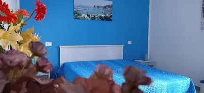 a blue bedroom with a bed and a vase of flowers at Nonna Giò House in Castellammare del Golfo
