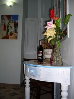 a table with a bottle of wine and a vase of flowers at Nonna Giò House in Castellammare del Golfo