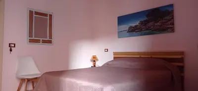a bedroom with a bed and a chair and a window at Nonna Giò House in Castellammare del Golfo