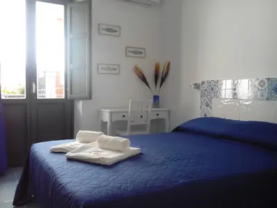 a bedroom with a blue bed with towels on it at Nonna Giò House in Castellammare del Golfo