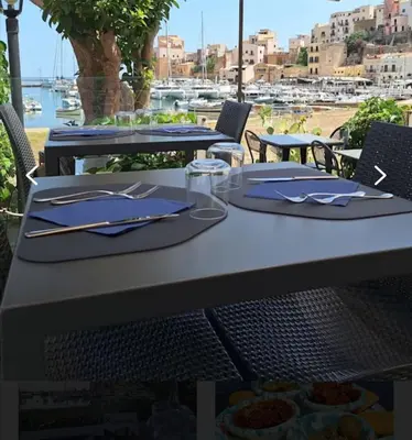 a table with plates and utensils on top at Monolocale La Chicca in Castellammare del Golfo
