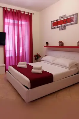 a bedroom with a large bed with pink curtains at BB45 in Palermo