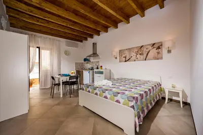 a bedroom with a bed and a kitchen with a table at Il Cortile in Castellammare del Golfo
