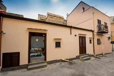 a white building with a door and a table at Il Cortile in Castellammare del Golfo