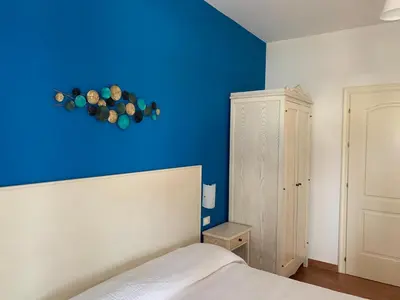 a blue bedroom with a bed and a blue wall at Villa Ancora Bed & Breakfast in San Vito lo Capo