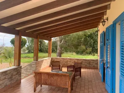 a patio with two benches and a table and chairs at Villa Ancora Bed & Breakfast in San Vito lo Capo