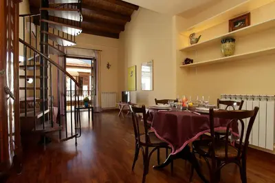 a dining room with a table and chairs and a staircase at Casa Matrangela in Palermo