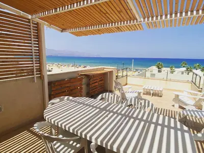 a patio with a table and chairs and the beach at Tonnara Apartments in Alcamo Marina