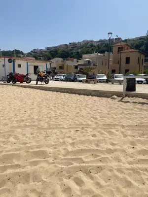 a sandy beach with motorcycles parked in a parking lot at Tonnara Apartments in Alcamo Marina