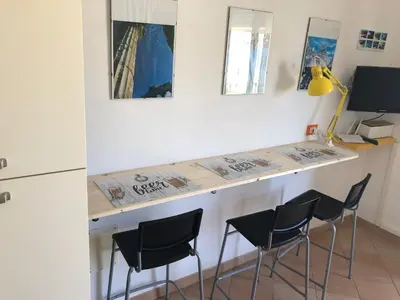 a kitchen with a counter with chairs and a desk at Tonnara Apartments in Alcamo Marina