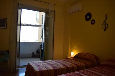 a bedroom with two beds and a door to a balcony at L'Aquilone B&B in Palermo