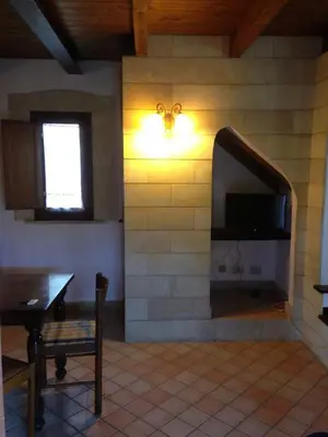 a living room with a stone wall with a television at Le 3 tartarughe in Lascari