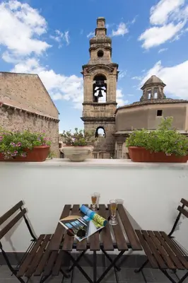a table and chairs on a balcony with a clock tower at Overseas - Penthouse with terrace - Attico - Palazzo San Matteo in Palermo