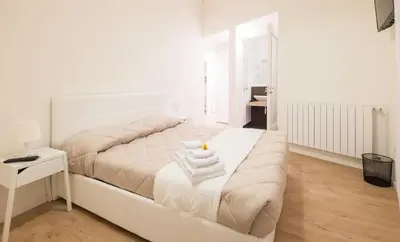 a white bedroom with a bed with towels on it at Dante 58 in Palermo